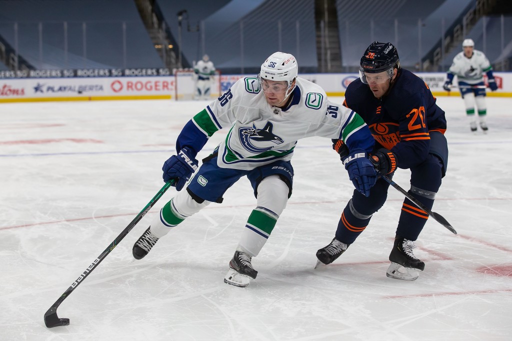 EDMONTON, AB - JANUARY 13: Slater Koekkoek #20 of the Edmonton Oilers defends against Nils Hoglander #36 of the Vancouver Canucks at Rogers Place on January 13, 2021 in Edmonton, Canada. (Photo by Codie McLachlan/Getty Images)